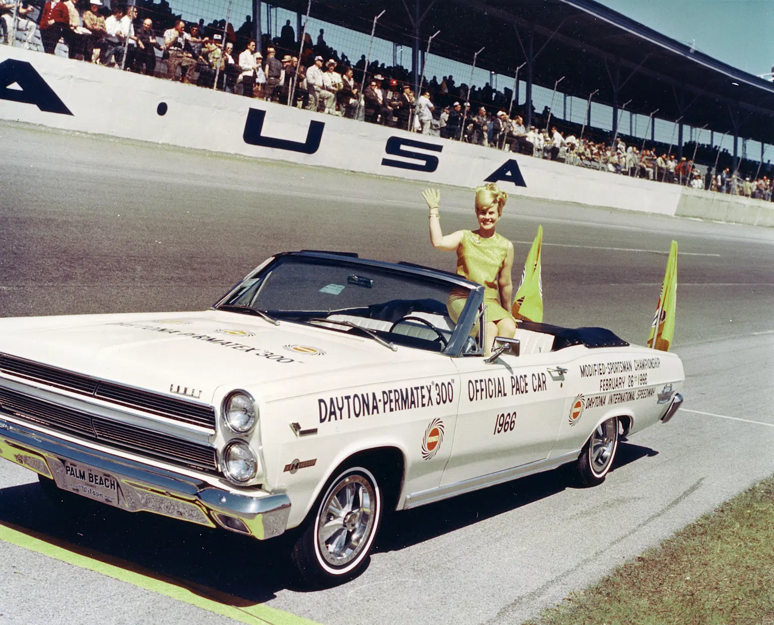 1966 Daytona Permatex 300 official pace car at Daytona International Speedway with a waving lady in vintage attire